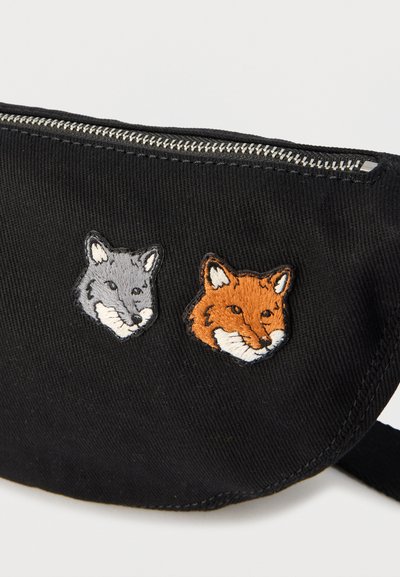 Pochette en tissu noir avec fermeture éclair argentée, ornée de têtes de renard gris et orange brodées à l'avant.