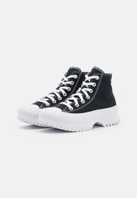 Sneakers high-top neri in tela con suole e lacci bianchi. Caratterizzati da una superficie testurizzata e dettagli di cucitura a contrasto.