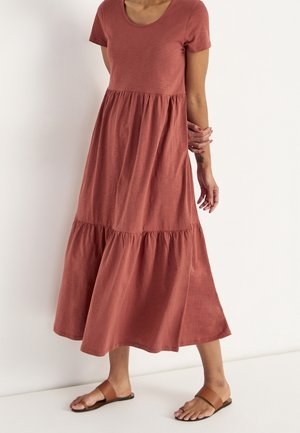 Robe longue à manches courtes couleur rouille avec un col rond, une taille plissée et une jupe à volants. Tissu lisse et longueur jusqu'aux chevilles.