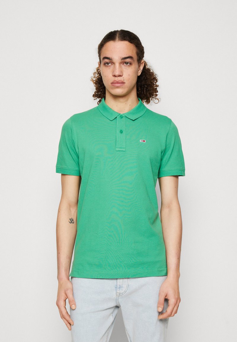 Polo verde in tessuto di cotone, con colletto classico, maniche corte e un piccolo logo sul lato sinistro del petto.