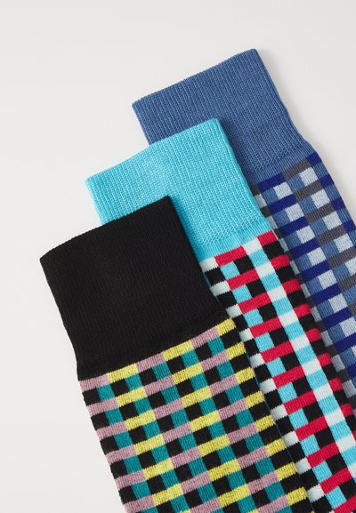 Trois paires de chaussettes à motifs : une noire avec des carreaux multicolores, une bleue avec des rayures et une bleu clair avec un motif à carreaux.