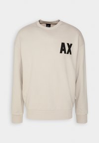 Felpa beige con collo rotondo, maniche lunghe e polsini a coste. Presenta un logo ricamato nero "AX" sul lato sinistro del petto. Tessuto morbido.