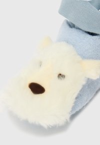 Plavi papuč s mekane tkanine, sa dizajnom puhastog bijelog lica medvjedića s crnim očima i smešnim nosom; elastična manžeta za sigurno prianjanje.