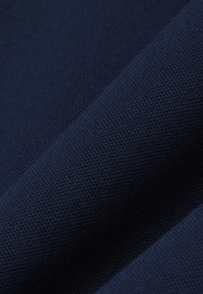 Tissu bleu marine foncé avec une texture étroitement tissée, montrant des plis subtils et une finition mate lisse.