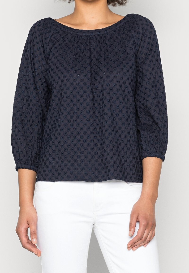 Blusa blu navy a trama con maniche a tre quarti, polsini elasticizzati e scollatura ampia. Presenta un sottile motivo floreale in tutto il tessuto.