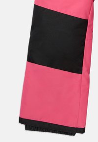 Sección inferior de pantalones de invierno impermeables en color rosa con una amplia franja horizontal negra y puño negro elástico.
