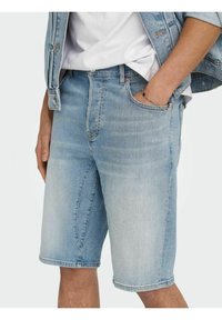 Vaaleansiniset farkkushortsit, joissa on suora leikkaus, viisi taskua, hienovarainen naarmutus ja raakapäärme polvien kohdalla.