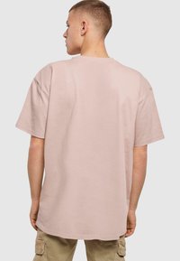 Lyserød bomuld t-shirt med en afslappet pasform, korte ærmer og rund halsudskæring. Bagsiden er ensfarvet uden synlige grafikker eller detaljer.
