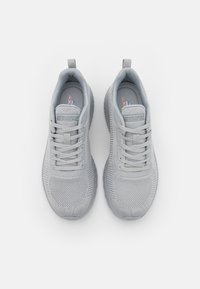 Light gray sneakers with mesh upper, lace-up closure, padded collar, and textured sole, featuring logo details on the tongue and side.