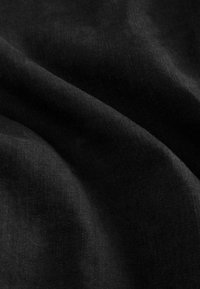 Black fabric with a smooth, slightly textured surface, showing soft folds and drapes, indicating a lightweight and flexible material.