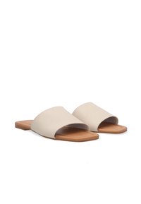 Béžové kožené sandály na ploché podrážce s otevřenou špičkou, s hladkým povrchem a minimalistickým designem.