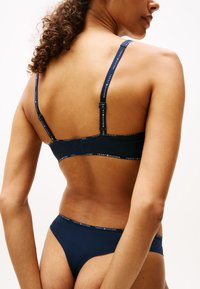 Marineblå lingerie-sett med en bralette med justerbare stropper og matchende høyhante truser, detaljert med elastisk trim med merke.