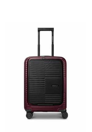 Hard-shell suitcase in dark red with black front pocket, four spinner wheels, and telescopic handle extended, branded REDOLZ.