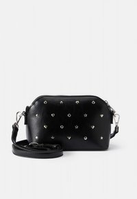 Sac bandoulière en cuir noir orné de clous en forme d'étoile et de cœur argentés. Dispose d'une fermeture éclair et d'une bandoulière amovible. Extérieur robuste et texturé.