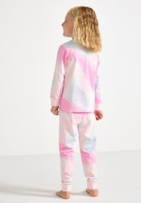 Set di pigiama rosa e bianco con maniche lunghe e pantaloni; presenta una stampa galattica pastello con stelle; tessuto morbido; polsini a coste.