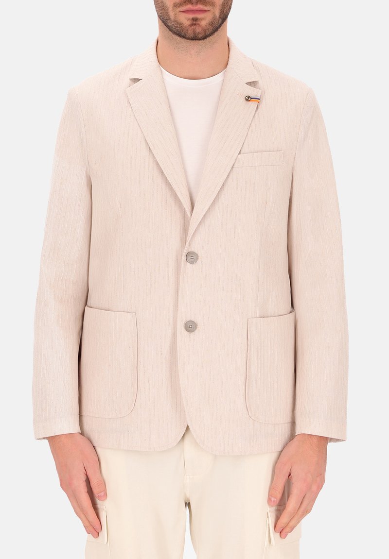 Blazer beige chiaro con righe verticali, chiusura a un bottone, rever a punta, due tasche frontali e una piccola spilla decorativa.