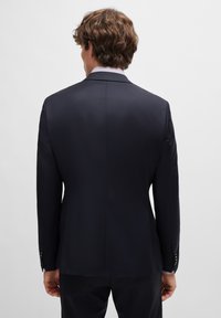 Marinblå blazer i ett mjukt tyg, med skräddarsydd passform, slits bak och knappade ärmslut med manschettknappar.