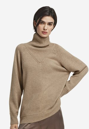 Pull en cachemire beige à col roulé avec une finition texturée, doté d'un détail de couture en forme de V et d'une coupe ample. Les poignets et l'ourlet côtelés complètent le design.