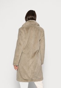 Beige faux pelsjakke med bred krave, lange ærmer og lige snit. Glat tekstur og knælængde design uden synlige lukninger.