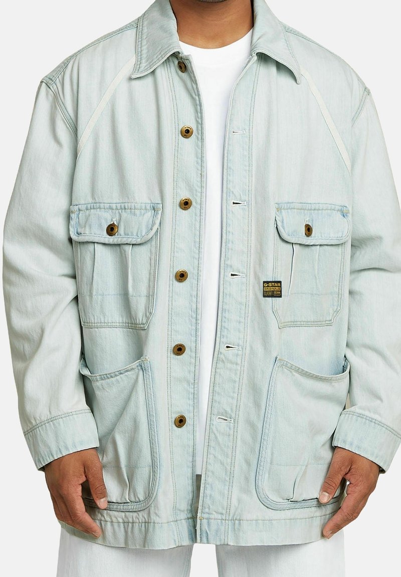 Ljusblå jeansjacka med avslappnad passform, som har fyra framfickor, bruna knappar och vita sömnadsdetaljer. Strukturerad tyg.