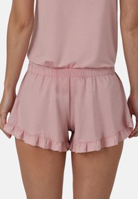 Shorts roses à volants fabriqués en tissu doux, avec une taille élastique et un design évasé avec une finition texturée à l'ourlet.