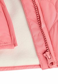 Rosa gesteppte Jacke mit weichem Fleece-Futter, ausgestattet mit einem passenden Reißverschluss und runden Taschen, die glattes Material und präzise Nähte zeigen.