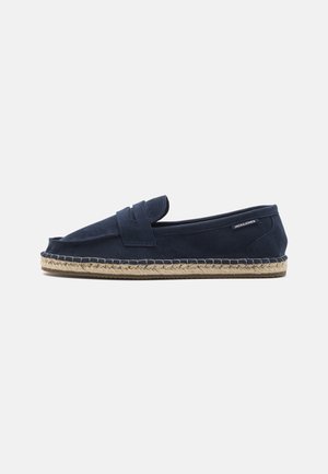 Mocasín de ante azul marino con suela trenzada de yute y etiqueta JACK & JONES en el talón, presentado sobre fondo blanco.