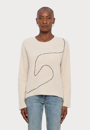 Beige trui van een gestructureerde brei, met een zwart-wit abstract lijnontwerp. Relaxte pasvorm met lange mouwen en een ronde halslijn.