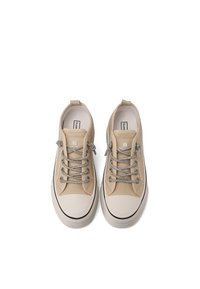 Zapatillas de lona beige de corte bajo con punteras y suelas de goma blancas, cordones de patrón gris y blanco, y tiradores en el talón.