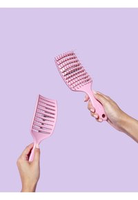 Deux peignes roses, un à dents larges et un autre pour démêler, placés sur un fond violet clair. Les deux ont des poignées en plastique lisses et des bouts ronds.