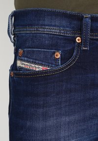 Mörkblå denimjeans med kopparnitar och sömmar. Den lilla framtasan visar en synlig etikett för Diesel Industry.