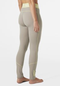 Lichtgrijze legging met een mesh-textuur, voorzien van gele accenten en een hoge tailleband. Strakke pasvorm en zijlogo-detail.