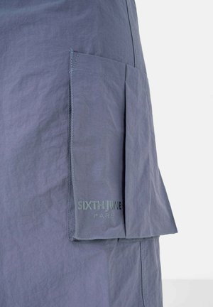 Falda de tela gris con un bolsillo lateral, que presenta detalles cosidos y un logo impreso "SIXTH JUNE PARIS" en letras discretas.