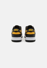 Juodos ir geltonos Nike sportinės bateliai su paminkštintu apvadu, turintys baltą vidurinį padas ir struktūruotą guminį padas. "Nike" logotipas ant kulno.