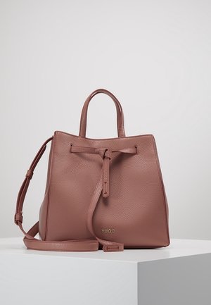 Bolso tote de cuero marrón con asas superiores, correa de hombro ajustable, detalle de nudo en el frente y pequeño logotipo "HUGO" en la parte delantera.