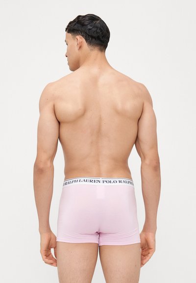 Roza bokserice iz gladkega blaga, z logotipom na pasu v mornarsko modri in beli barvi, ki poudarjajo prilegajočo se zasnovo in čiste linije.