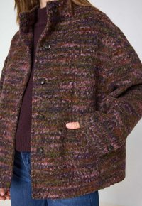 Veste en laine avec un design texturé dans des teintes de vert, de violet et de rose. Comprend un col relevé, une fermeture à boutons et des poches latérales.
