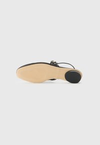 Black sandal featuring a strappy design, flat sole with textured rubber, and a round heel. The sole is beige with a smooth finish.