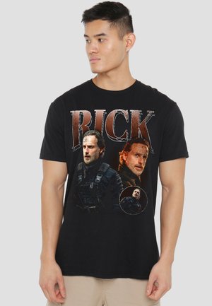Man wearing black t-shirt with three graphic portraits of a bearded man in tactical gear and the word "RICK" in large letters.