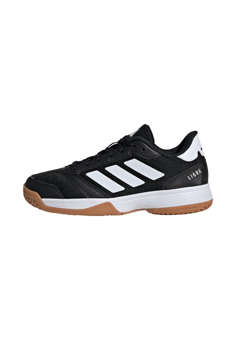 Chaussure de sport noire avec des rayures et des accents blancs. Présente une tige texturée, un col rembourré et une semelle extérieure en caoutchouc gomme. Nom du modèle "Ligra" sur le talon.