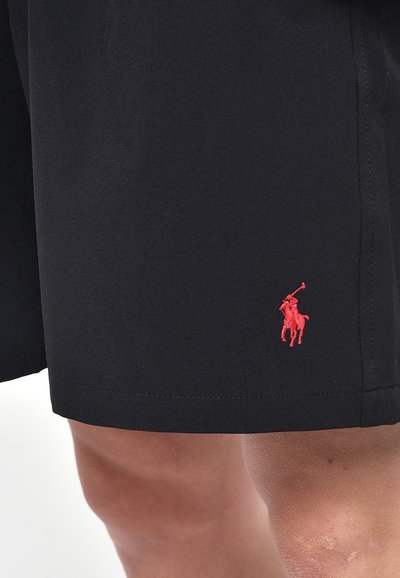 Pantaloni corti neri con un logo ricamato rosso sulla gamba sinistra, realizzati in un tessuto liscio con una vestibilità su misura e dettagli di cucitura minimi.