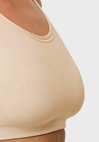 Nude mesh sportbh med rund halsringning och sömlösa kanter, med en texturerad tyg och en åtsittande design för stöd.