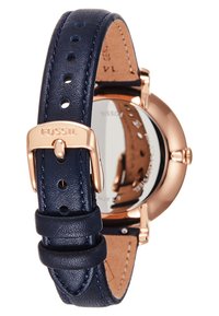 Montre Fossil avec un boîtier rond en acier inoxydable doré rose, un bracelet en cuir bleu foncé avec couture, et un cadran argenté poli.