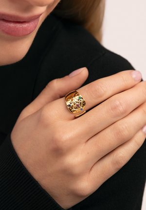 Anillo de oro con superficie texturizada que presenta múltiples piedras preciosas de varios colores, diseñado con un estilo audaz y escultórico.
