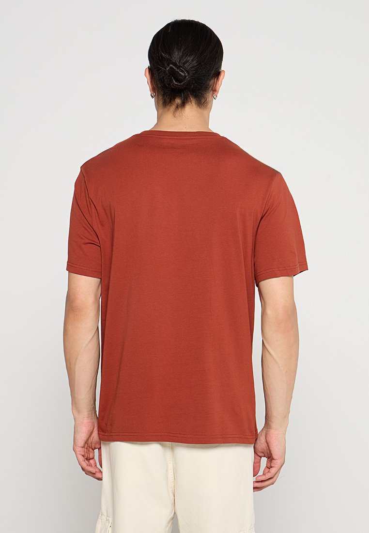 T-shirt a maniche corte color ruggine, realizzato in cotone, con scollatura a girocollo e vestibilità comoda. Texture liscia con cuciture minime.