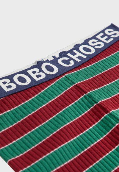 Tissu à rayures côtelées en rouge et vert avec des accents blancs. Présente une taille en marine affichant "BOBO CHOSES" en lettres majuscules.