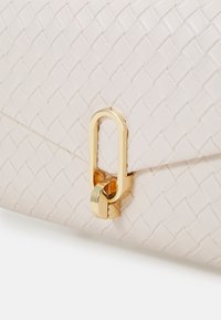 Woven-texture light pink leather bag with a gold-toned, oversized clasp and hinge detail. Smooth finish with geometric pattern.