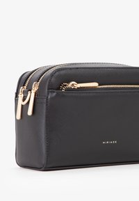 Schwarze rechteckige Kosmetiktasche mit goldfarbenen Reißverschlüssen und Akzenten; aus strukturiertem Material gefertigt; verfügt über ein Markenlogo an der Seite.