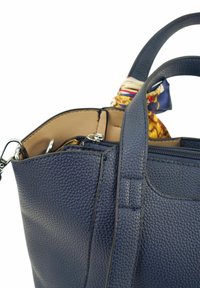 Marineblauwe leren handtas met een gestructureerd oppervlak, dubbele handgrepen en een gestructureerde sjaal die de bovenkant van de tas accentueert.