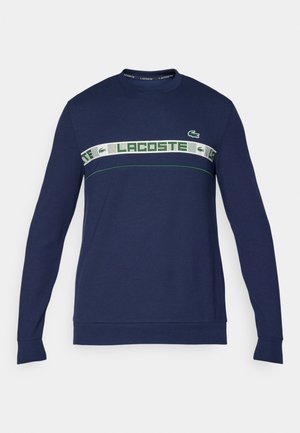 Felpa blu navy a maniche lunghe realizzata in cotone, con una fascia orizzontale bianca e verde e il marchio "LACOSTE" e il logo sul petto.